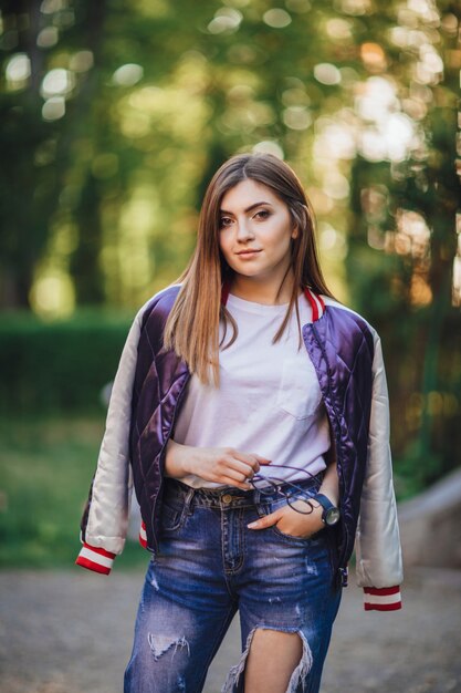 Portrait d'une belle jeune fille à lunettes en jeans avec un pantalon élégant