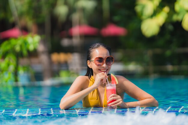 Portrait belle loisirs de jeune femme asiatique se détendre sourire avec du jus de pastèque autour de la piscine dans l&#39;hôtel resort