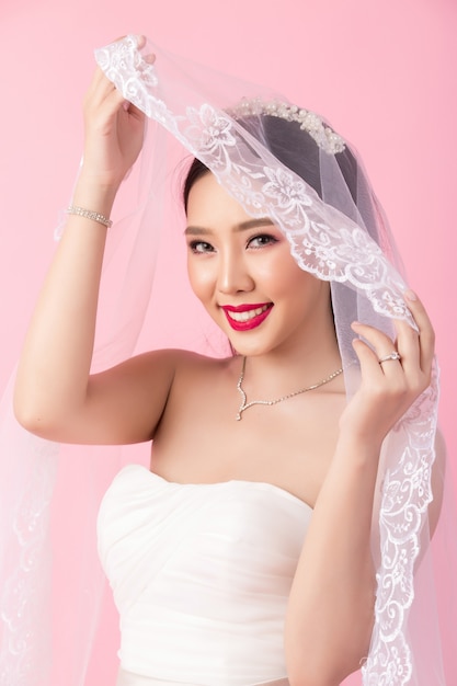 Portrait de la belle mariée asiatique en studio rose