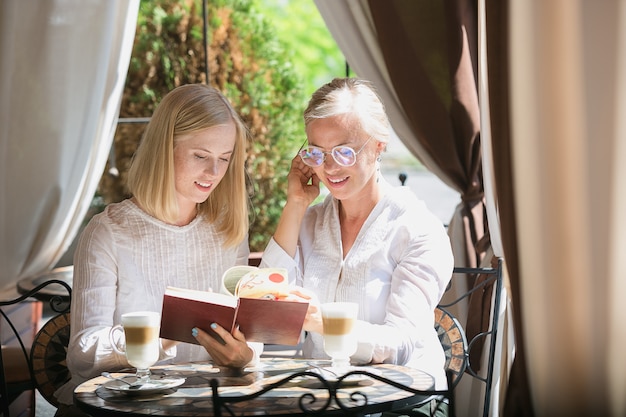 Portrait de la belle mère mature et sa fille tenant la tasse assis à la maison