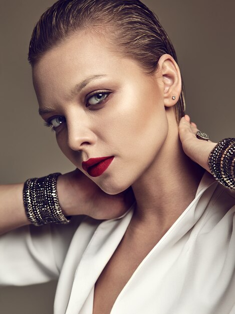 Portrait de la belle mode élégante femme brune modèle avec maquillage de soirée et lèvres rouges en veste blanche