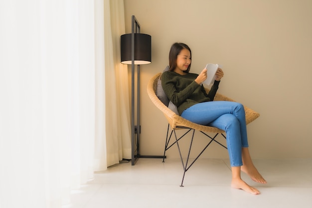 Portrait de belles jeunes femmes asiatiques lecture livre et assis sur une chaise canapé