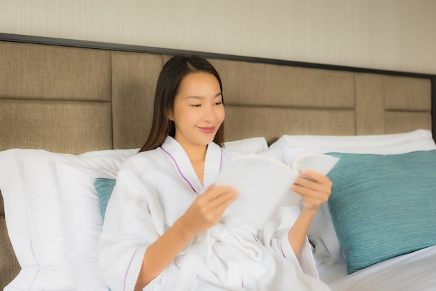 Portrait de belles jeunes femmes asiatiques avec tasse de café et livre sur lit