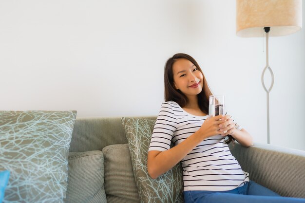 Portrait de belles jeunes femmes asiatiques tenant un verre d'eau sur un canapé