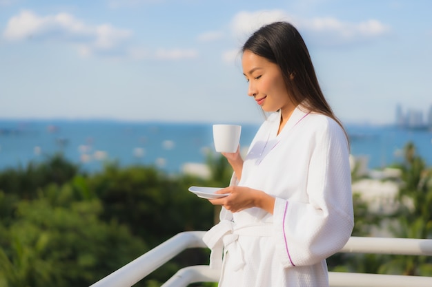 Portrait de belles jeunes femmes asiatiques tenir la tasse de café à la main autour de la vue extérieure