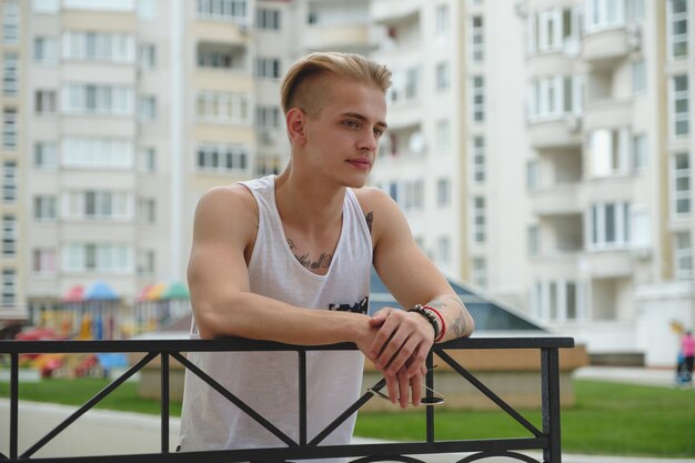 Portrait blond hipster garçon avec des tatouages et des cheveux élégants