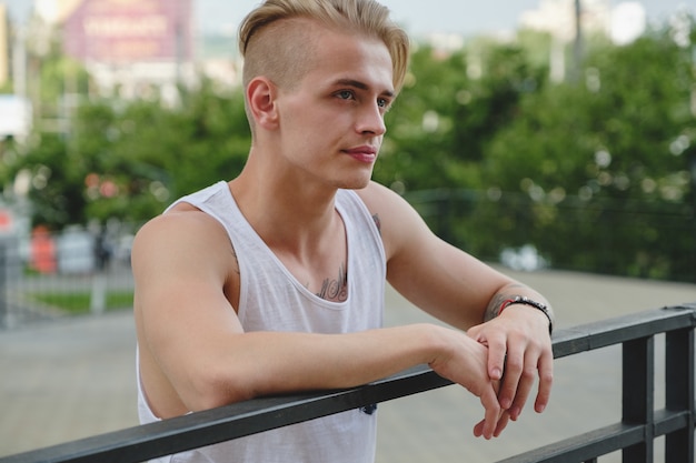 Portrait blond hipster garçon avec des tatouages et des cheveux élégants