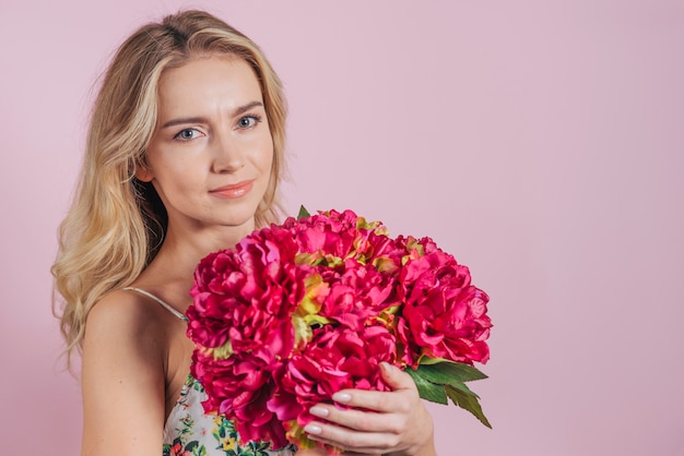 Portrait de blonde jeune femme tenant un bouquet de fleurs dans les mains