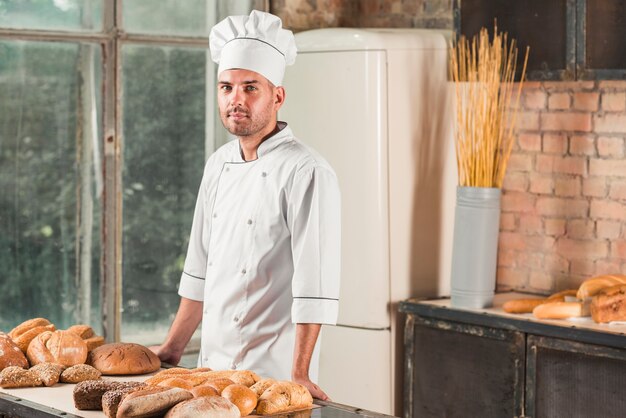 Portrait d&#39;un boulanger mâle avec divers pains cuits au four