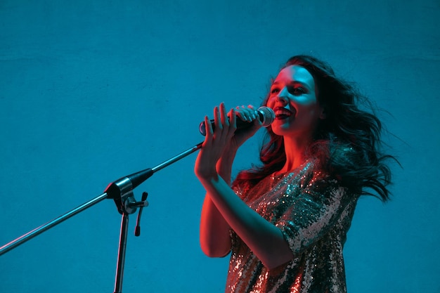 Portrait de chanteuse caucasienne isolé sur bleu en néon