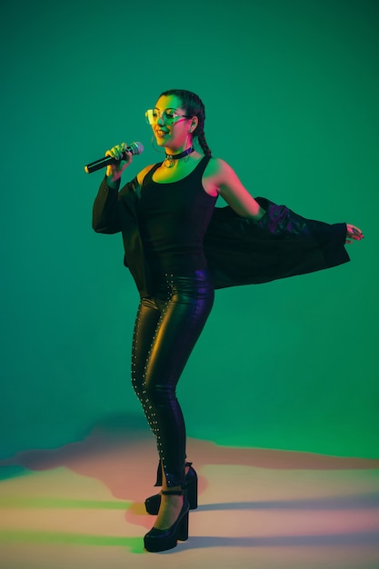 Photo gratuite portrait de chanteuse isolée sur mur vert studio en néon