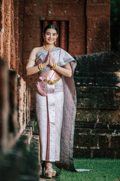 Portrait d'une charmante femme asiatique portant une belle robe thaïlandaise typique de la culture de l'identité de la Thaïlande dans un ancien temple ou un lieu célèbre avec une pose gracieuse