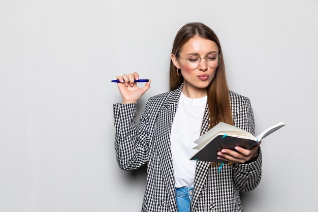 Portrait charmante femme ayant le bloc-notes et un stylo dans les mains de planification, d'expertise, d'analyse isolé