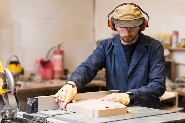 Photo gratuite portrait d'un charpentier ajustant le bloc de bois dans l'atelier