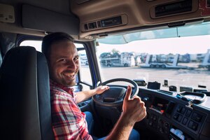 Photo gratuite portrait de chauffeur de camion assis dans son camion tenant les pouces vers le haut