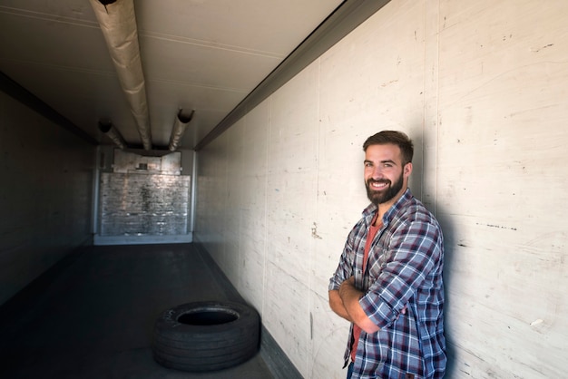 Photo gratuite portrait de chauffeur de camion avec les bras croisés debout dans une remorque de camion vide