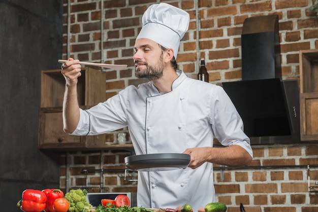 Photo gratuite portrait de chef masculin appréciant l'odeur de la nourriture préparée
