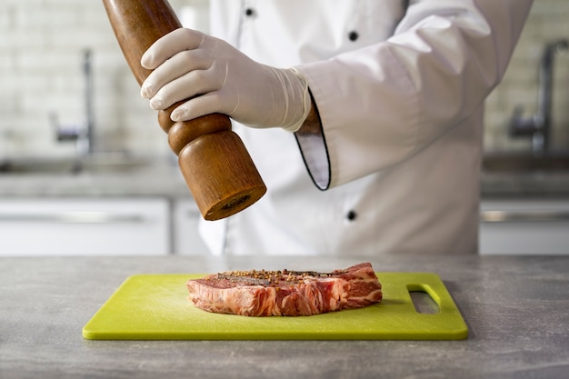 Portrait de chef masculin dans la cuisine préparant la viande