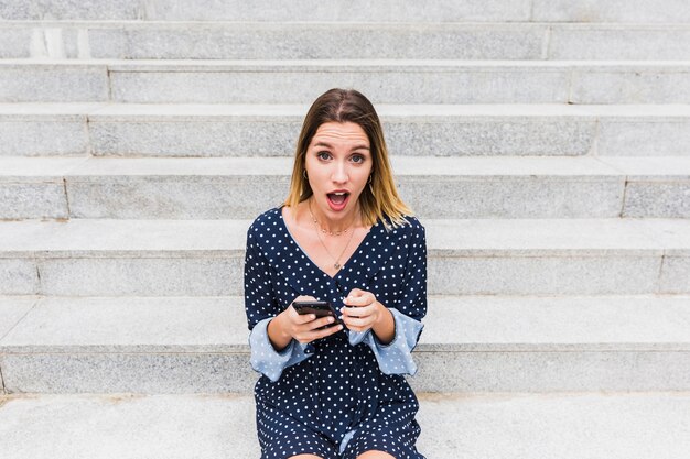 Portrait, choqué, femme, séance, escalier, tenue, téléphone portable