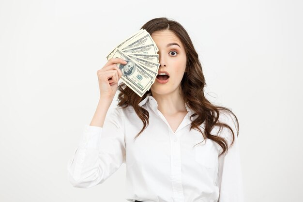 Portrait choqué jeune femme d'affaires debout et tenant de l'argent isolé sur fond blanc