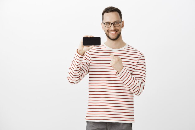 Portrait de client de magasin mignon impressionné heureux avec des poils dans des lunettes tendance noires