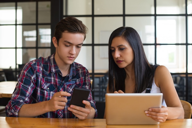 Portrait de collègues sérieux à l&#39;aide d&#39;un smartphone et d&#39;une tablette PC