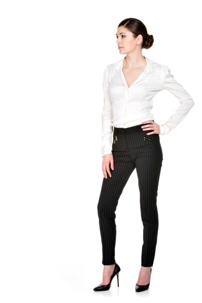 Portrait complet de la belle jeune femme en chemise blanche et pantalon noir debout.