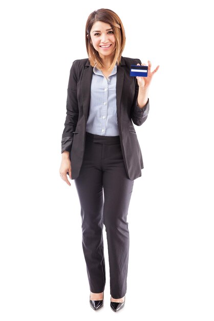 Portrait complet d'une belle représentante de banque tenant une carte de crédit et invitant les clients à en faire la demande