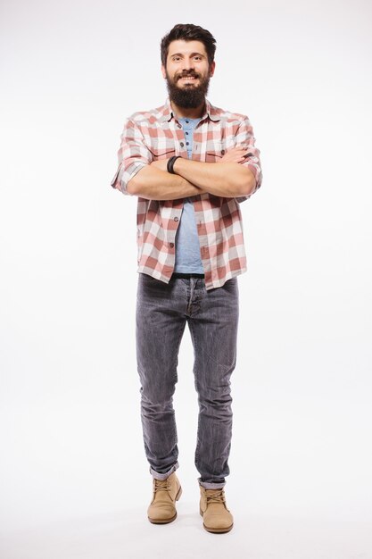 Portrait complet du corps d'un jeune homme décontracté souriant, isolé sur un mur blanc