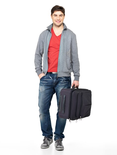 Portrait complet d'un homme heureux souriant avec une valise grise isolé sur blanc