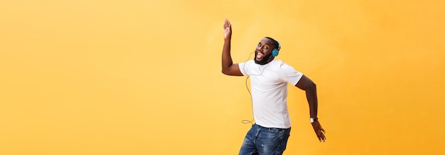 Photo gratuite portrait complet d'un jeune homme afro-américain cerise écoutant de la musique avec des écouteurs et d