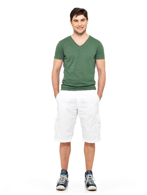 Portrait complet de sourire heureux bel homme en short blanc et t-shirt vert isolé sur blanc