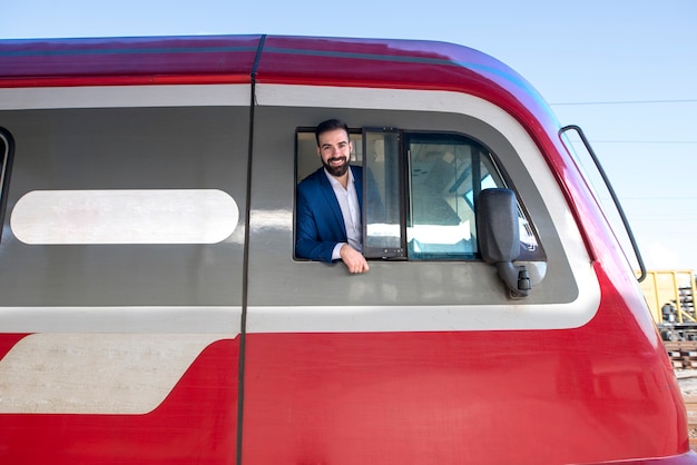 Photo gratuite portrait de conducteur de métro se pencha hors de son cockpit de fenêtre de train à la gare avant le départ