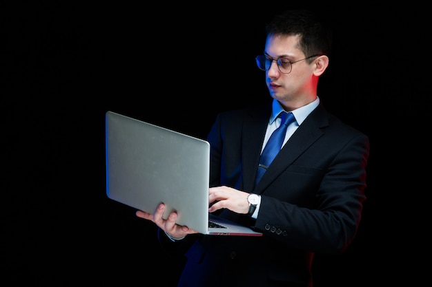 Portrait de confiant bel homme d'affaires élégant tenant un ordinateur portable dans ses mains
