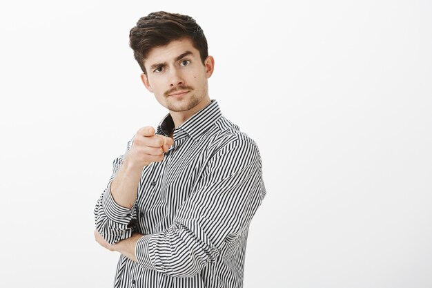 Portrait de confiant d'entreprise masculine joyeuse avec moustache, pointant et soulevant le sourcil, personne invitant à aller au bar ensemble, aproving bon point de vue