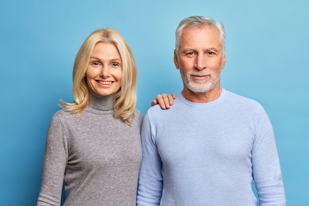 Portrait de couple d'âge mûr se tenir côte à côte regarder directement la caméra ont des expressions satisfaites