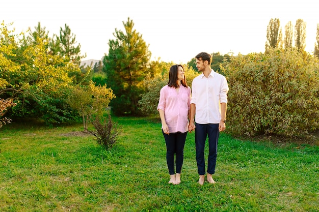 Portrait de couple enceinte gai se regardant dans le parc