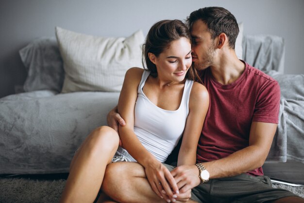 Portrait de couple à la maison ensemble assis sur le sol près du canapé