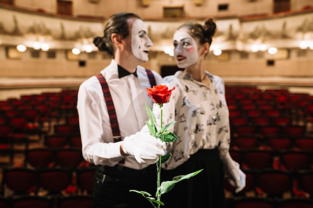 Photo gratuite portrait de couple mime tenant une rose rouge dans l'auditorium