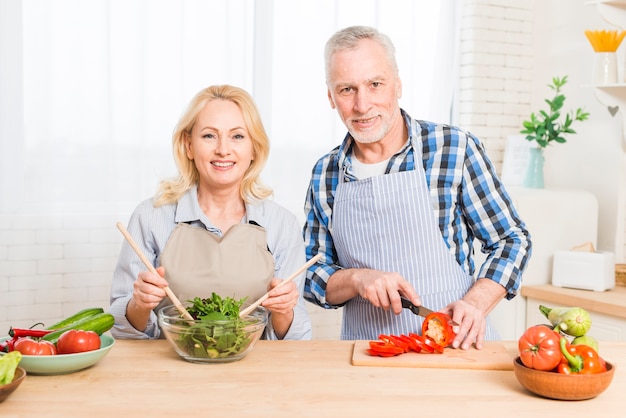 Portrait d&#39;un couple de personnes âgées préparant la nourriture dans la cuisine