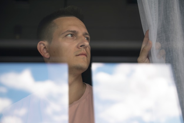 Photo gratuite portrait créatif d'un homme avec des rideaux et des ombres depuis la fenêtre