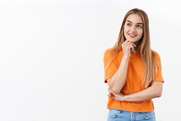 Portrait d'une curieuse jolie fille blonde cueillant un produit, regardez à gauche un espace blanc vide comme si vous choisissiez