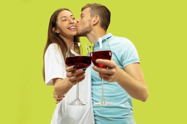 Portrait de demi-longueur de beau jeune couple isolé. Femme et homme debout avec des verres de vin rouge. Expression faciale, été, concept de week-end. Couleurs à la mode.