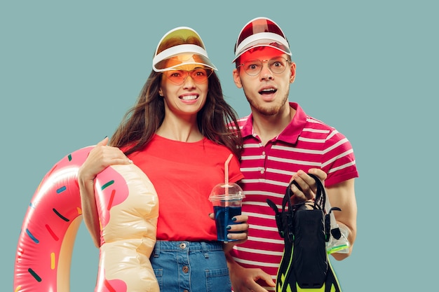 Portrait de demi-longueur de beau jeune couple isolé. Femme souriante et homme en casquettes et lunettes de soleil avec équipement de natation. Expression faciale, été, concept de week-end.