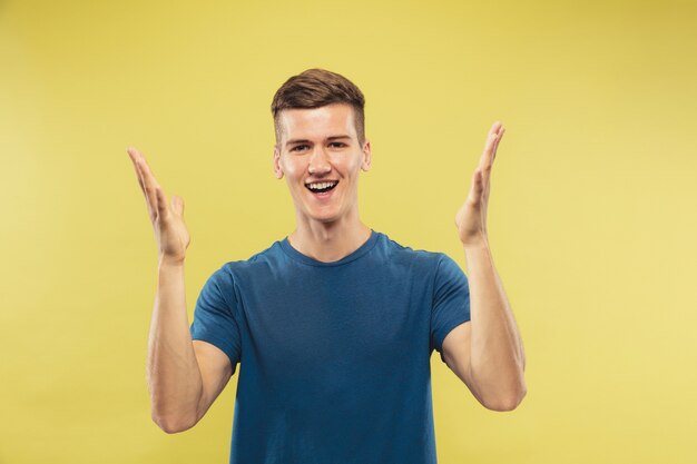 Portrait demi-longueur du jeune homme caucasien sur l'espace jaune. Beau modèle masculin en chemise bleue