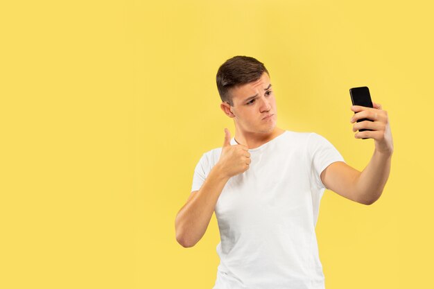 Portrait demi-longueur du jeune homme caucasien sur studio jaune