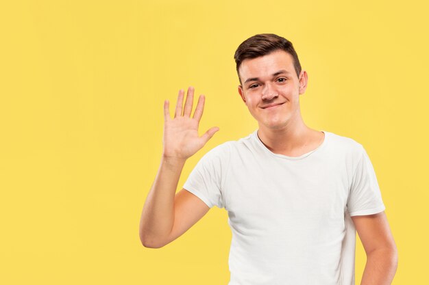 Portrait demi-longueur du jeune homme caucasien sur studio jaune