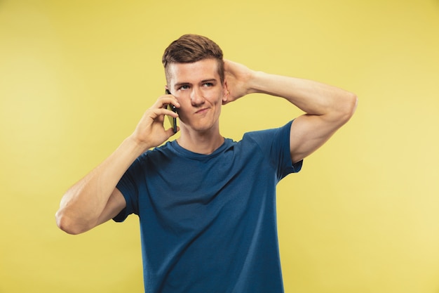 Portrait demi-longueur du jeune homme caucasien sur studio jaune