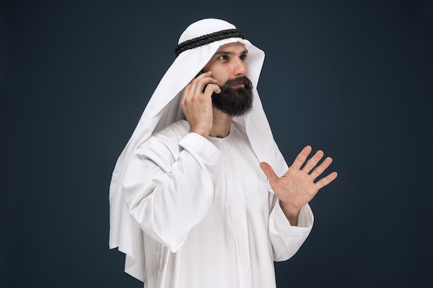 Portrait demi-longueur de l'homme arabe sur studio bleu foncé