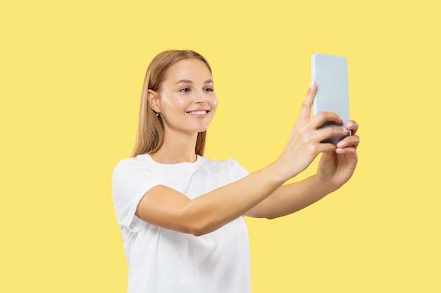 Portrait de demi-longueur de jeune femme caucasienne sur studio jaune